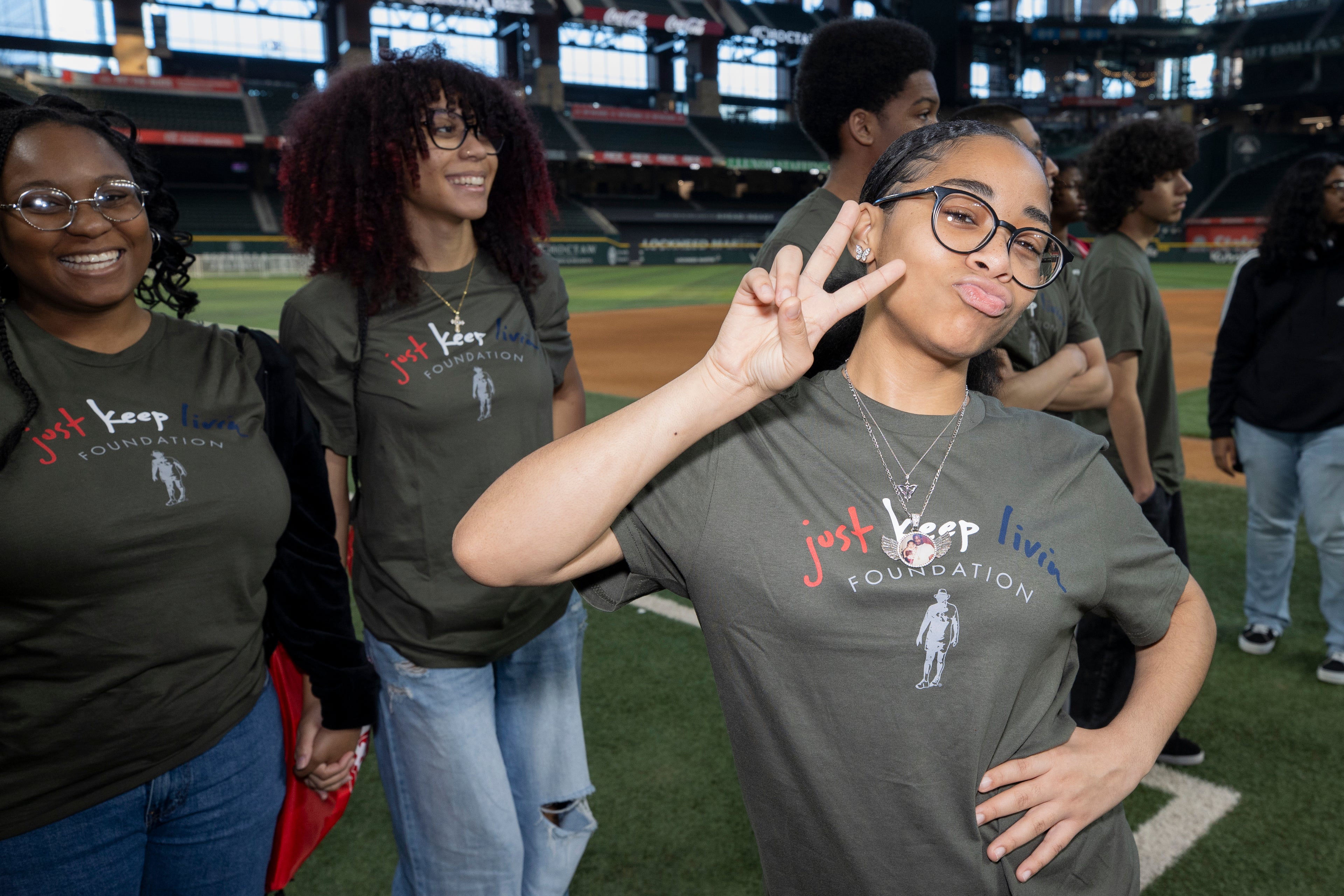 Group of people wearing 'Just Keep Livin' t-shirts at a sports event.