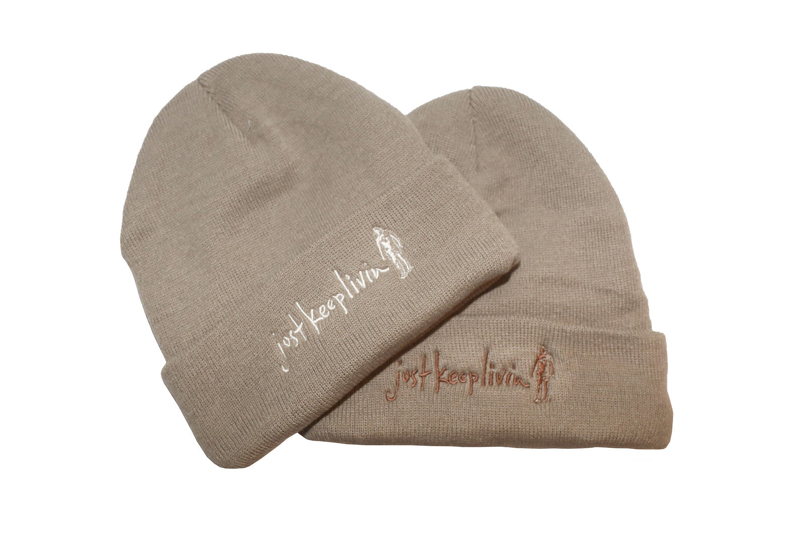 Two light tan fleece-lined beanies with embroidered text on the cuff, one displayed upright and the other turned sideways.