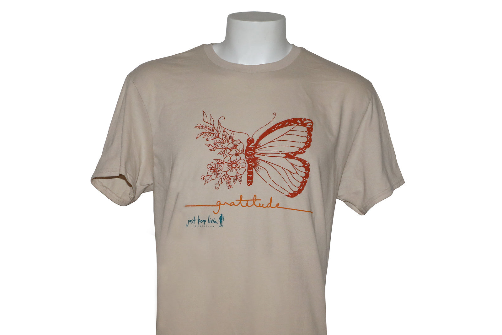 A light tan colored t-shirt with a graphic design of a butterfly and the phrase 'GRATITUDE IS THE ATTITUDE' printed on the front.