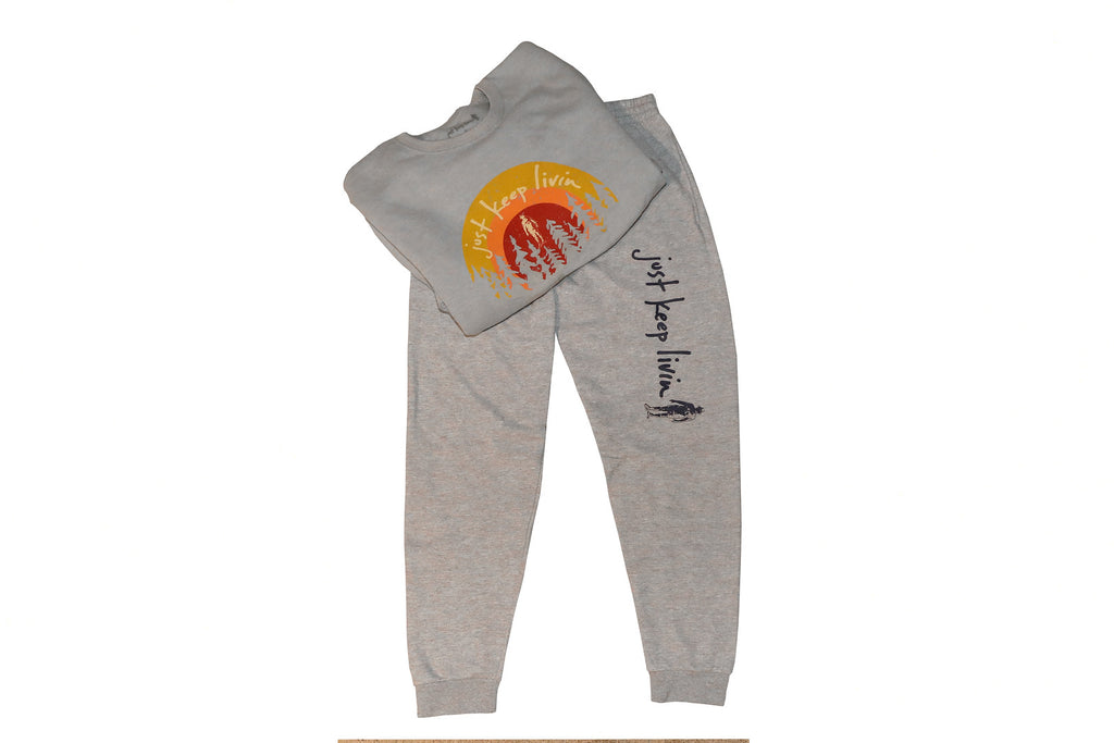 Gray jogging sweatshirt and pant set. sunrise yellow, orange, and red just keep livin logo with tree backdrop on sweatshirt. just keep livin text logo on left pant leg above knee. 