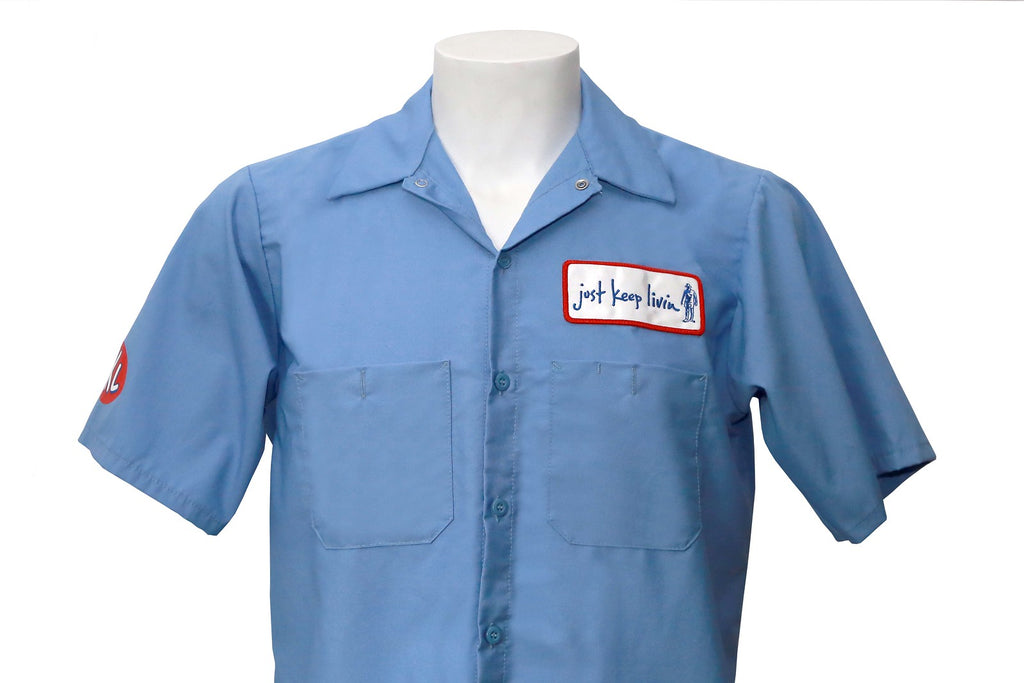 Front of light blue mechanic shirt with just keep living patch on left breast. 