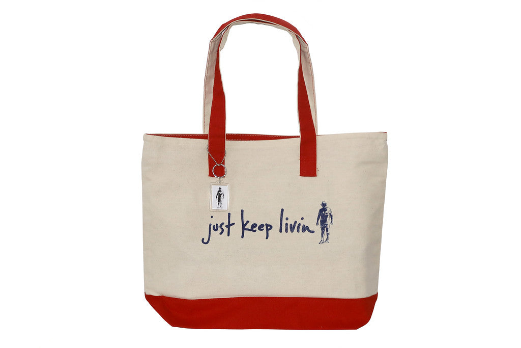 Just Keep Living tan tote bag with red lining on bottom and red handle. 