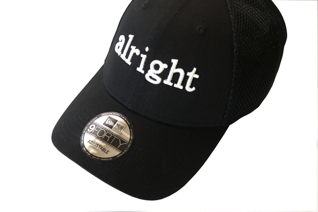 A black baseball cap with the word 'Alright' embroidered in white on the front and a gray mesh back panel.